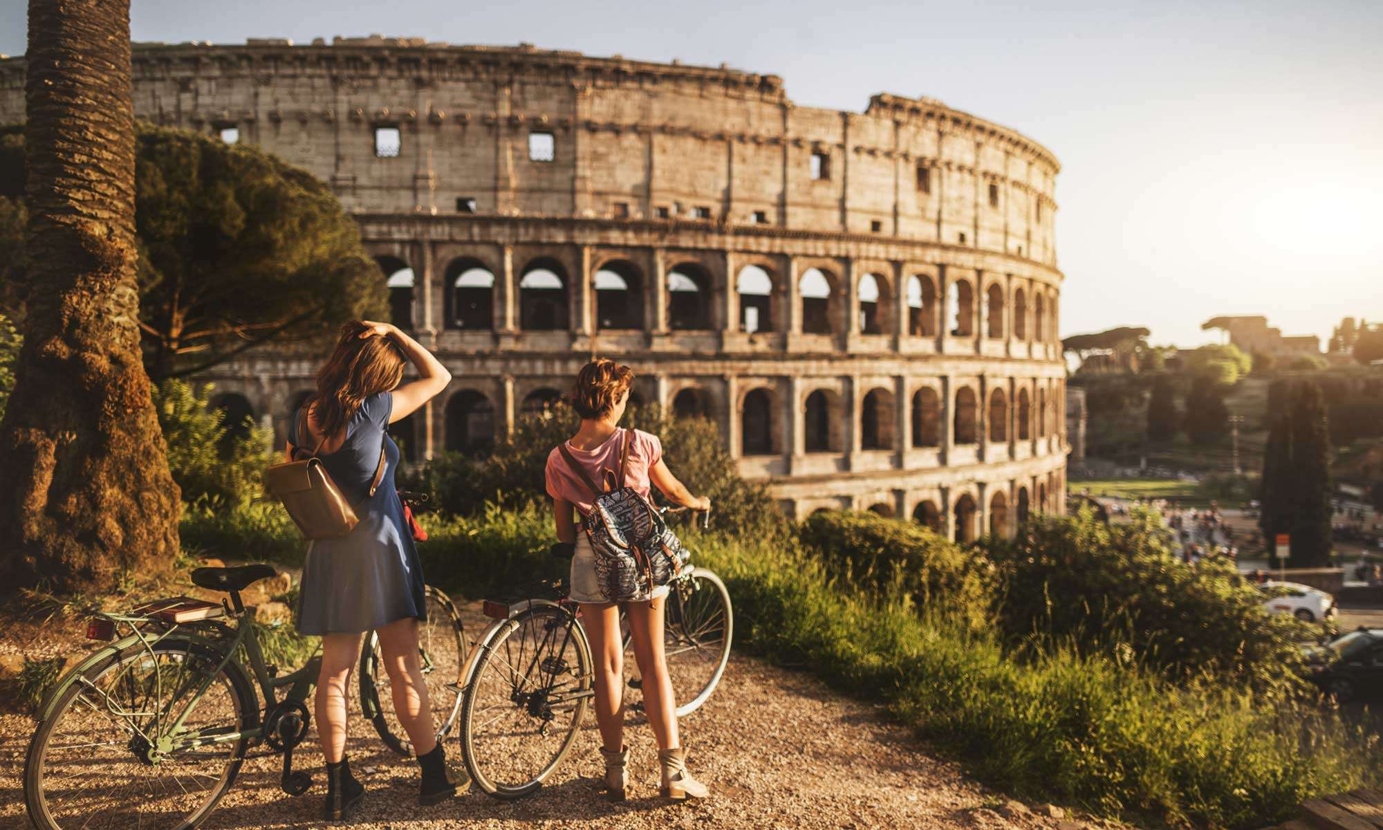 Two people on bikes look at the Colloseum in Rome