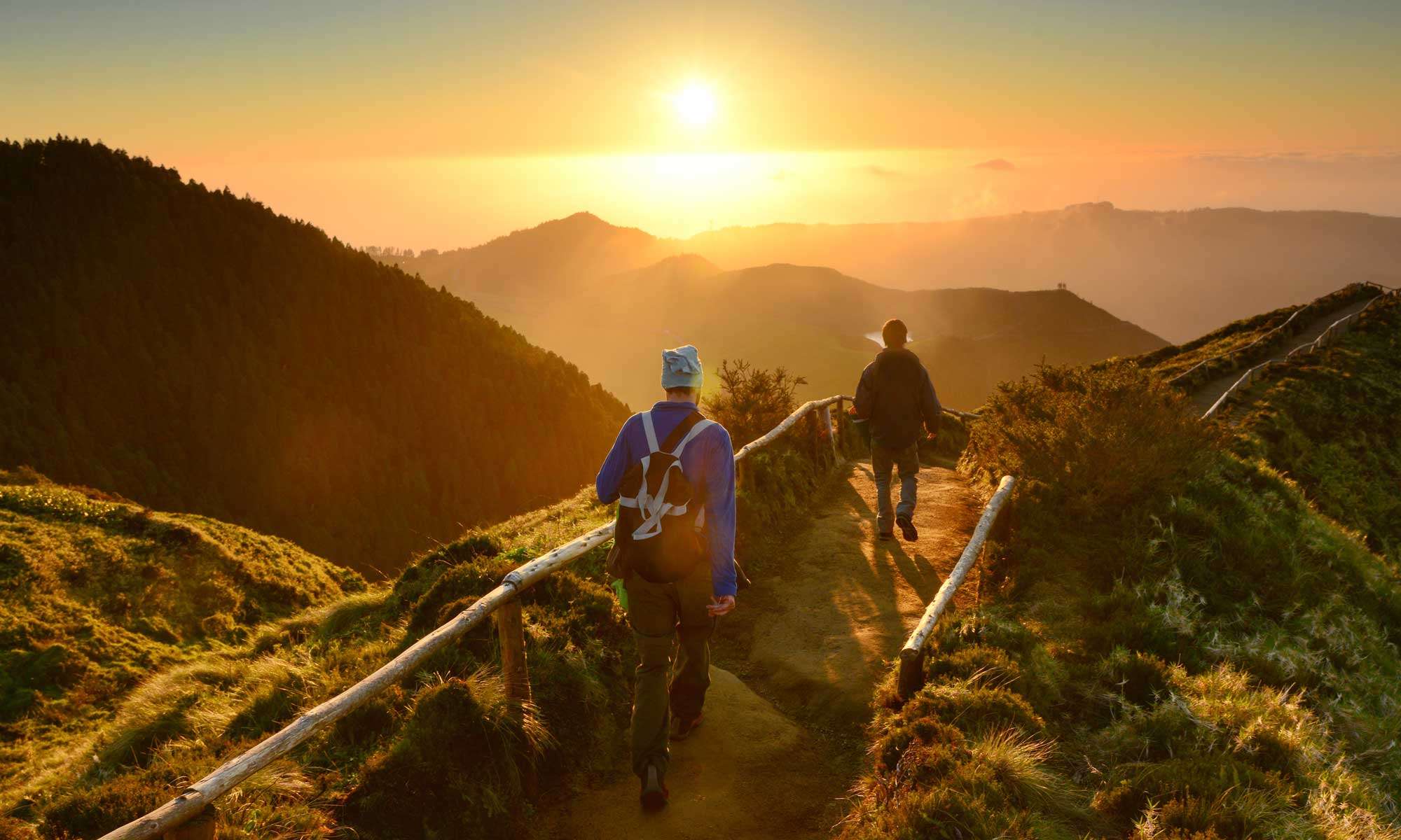 Two people hiking across a ridge during the sunrise